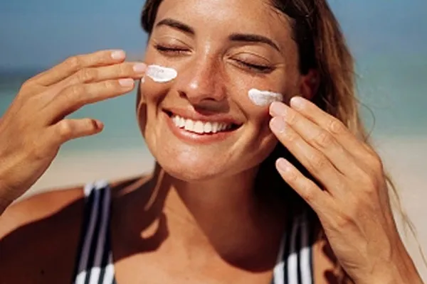 Eine Frau trägt Sonnencreme auf die Wangen auf